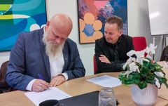 Rektor Peter Brink Thomsen ser på, mens udvalgsformand Thue Lundgaard skriver partnerskabsaftalen under. Foto: Halsnæs Kommune