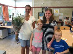 Pernille får blomster af to elever og deres mor