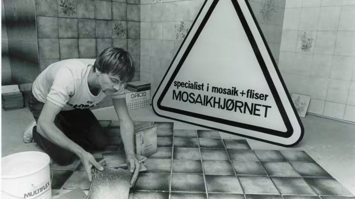Jørn, som lægger fliser i butikken i Glostrup, 1984. Fliserne findes stadig under den nuværende udstilling.