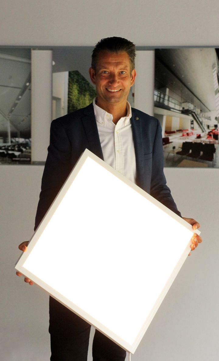 Det ny DAMPA LED-lyspanel, som direktør Michael Nykjær her præsenterer, kan let og hurtigt klikkes på plads i et DAMPA Clip-in systemloft. Foto: PR.