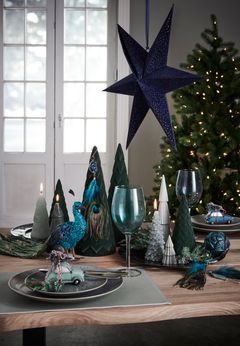 Julens farver er ikke kun rød og grøn. Med turkise elementer på julebordet får du et anderledes, men elegant udtryk, der står smukt til det mørkegrønne juletræ. Foto: PR.