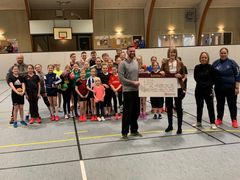 Dorthe Quist, kunderådgiver i Sparekassen Kronjylland i Odense og Morten Henriksen, håndboldtræner for U11-pigerne sammen med klubbens unge spillere.
