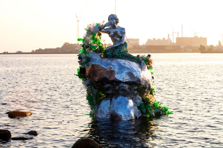 En ny, bæredygtig havfrue, svøbt i plastaffald fra havnen, blev i dag afsløret på Langelinie i København. Hun er sammensat af hundredvis af genanvendelige øldåser, der er limet sammen med en nyudviklet lim, som snart vil erstatte plastik omkring Carlsbergs 6-pack-øl og spare 1200 tons plast om året.