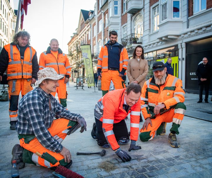 Borgmester Jesper Frost Rasmussen lægger sammen med brolæggerne den sidste sten i Esbjergs nye gågade. Foto: Esbjerg Kommune
