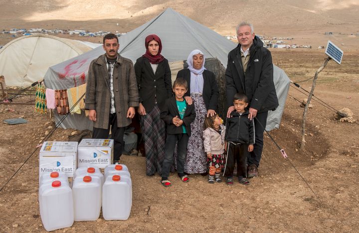 Kamal og hans familie kan nu holde varmen i deres slidte telt takket være varmeapparater og brændstof fra Mission Øst med penge fra tv-indsamlingen i september. Til højre ses Mission Østs generalsekretær Kim Hartzner sammen med familien.