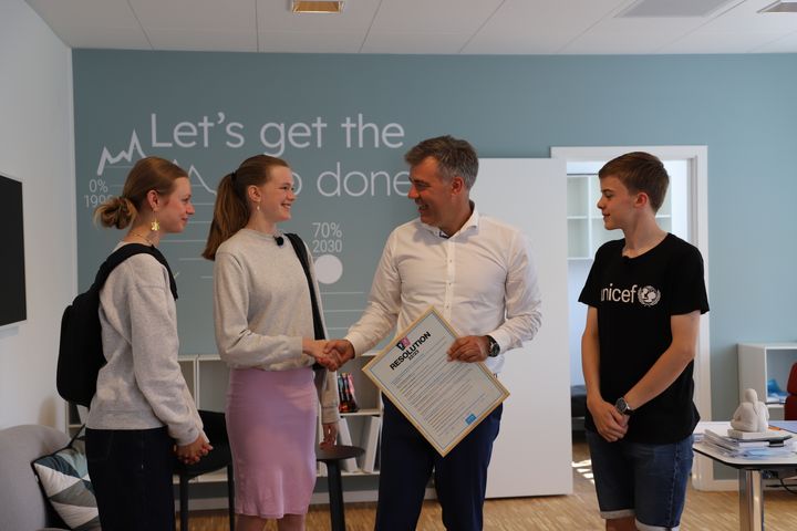 Mathias, Le og Caroline fra UNICEFs Nationale Rettighedsråd giver hånd til klimaminister Lars Aagaard efter at have overrakt ham rådets resolution.