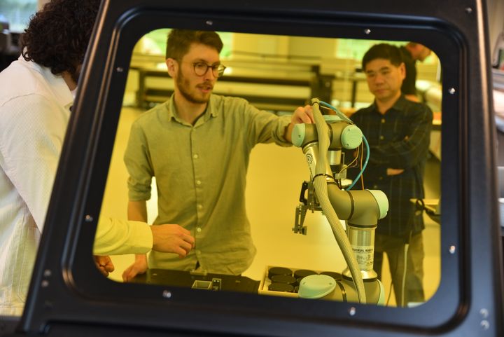 Ingeniørstuderende og ph.d.-studerende arbejder på robotarmen under vejledning fra lektor Xuping Zhang (th). Foto: Jesper Bruun
