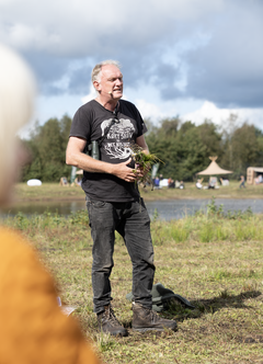 Biolog Morten D.D. står med en tot græs i hænderne, mens han holder oplæg.