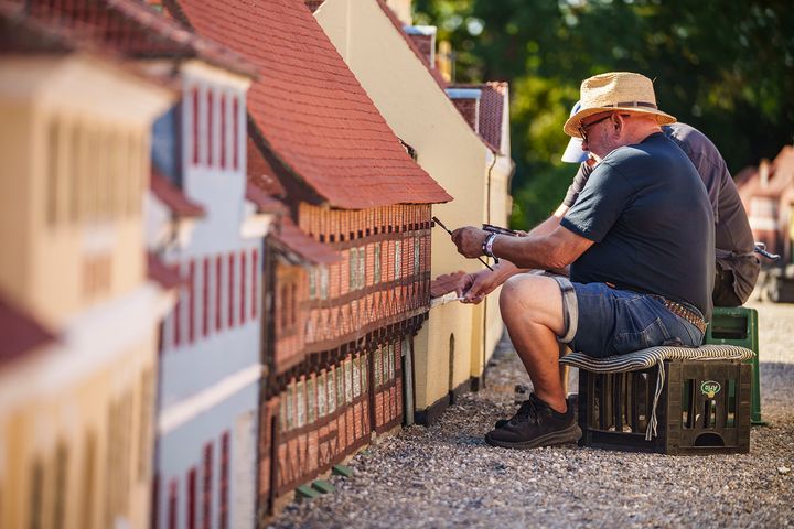 Et par frivillige entusiaster maler et miniturehus i Kjøge Miniby.