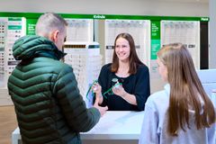 En mand og en pige får udleveret beskyttelsesbriller af en butiksekspedient i en Louis Nielsen-butik.