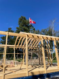 En næsten færdig trækonstruktion af Hampens Hus med dansk flag i toppen.