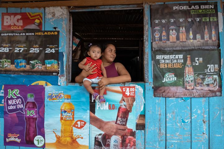 Damaris Amaringo holder sin 11 måneder gamle datter, Luana Guerra, som sidder i vinduet på familiens café i Iquitos, Peru.
