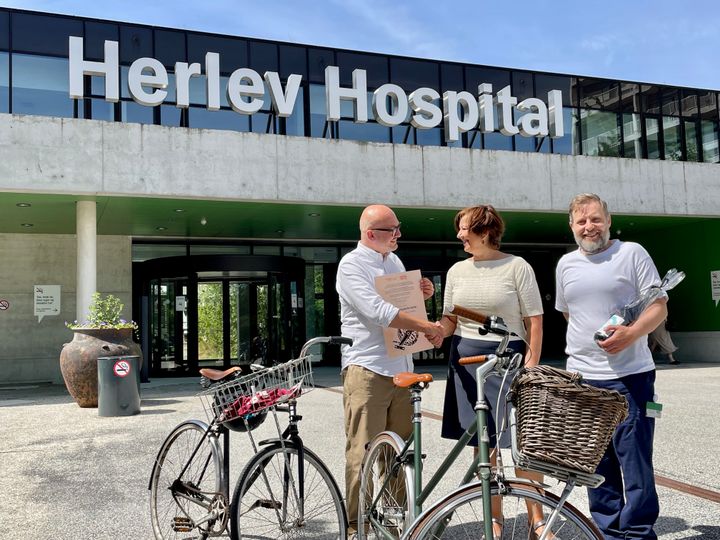 Vicedirektør i Cyklistforbundet, Jane Kofod, overrækker prisen til hospitalsdirektør Niels Würgler Hansen (tv) og fysioterapeut og næstformand i Virksomheds MED-udvalget (VMU) Anders Breinholt Nielsen.