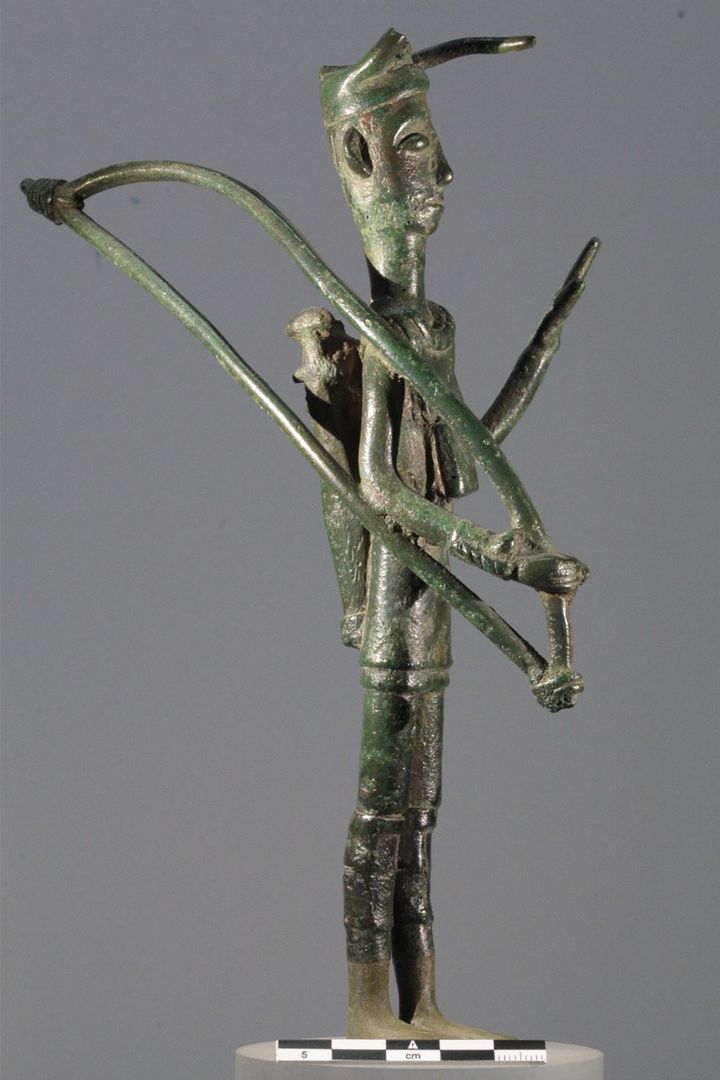 Foto af Heide W. Nørgaard: Krigerskulpturen (bronzettI) fra Abini i det centrale Sardinien. De fleste bronzetti er afbildet med et våbensæt bestående af forskellige kombinationer. Denne bronzettI tilhører bueskyttegruppen og er udstyret med sværd, bue, pile samt dele af kropspanser, herunder den typiske hornede hjelm. Disse hornede hjelme bæres af krigerstatuetterne. Foto taget med tilladelse af Museo Archaeologica Nazionale di Caglairi.