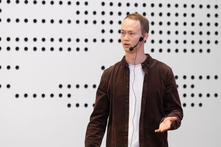 En person holder en præsentation med mikrofon i et auditorium.