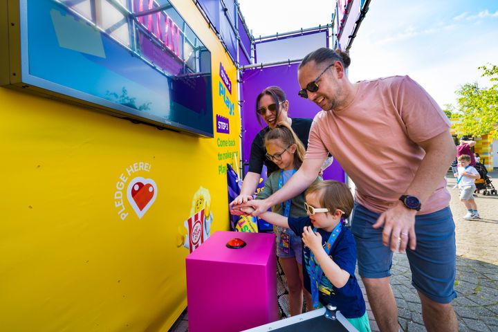 Familie indgår legepagt ved at trykke på knappen til LEGO® Festival og donerer legetimer til børn i udsatte positioner.