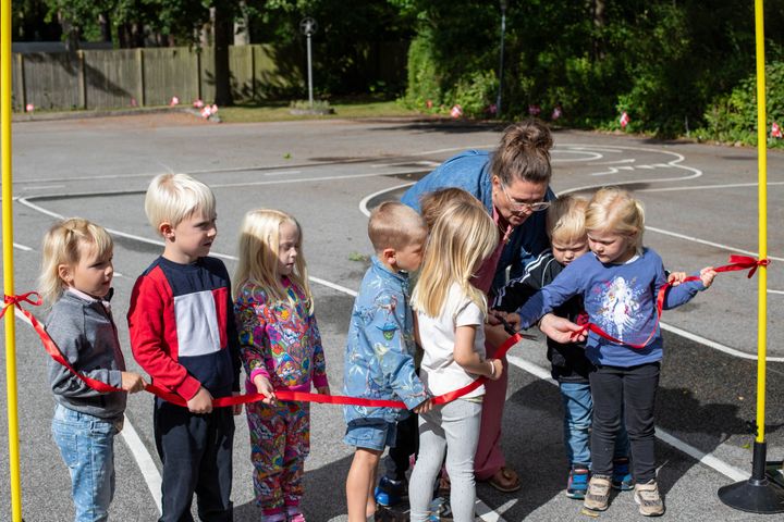 Lærkereden er certificeret idrætsbørnehave og har nu endelig fået trygge rammer at øve cykling i. Her hjælper børnene leder Signe Løgsted med at klippe snoren og indvie den nye trafikbane, som er blevet etableret med støtte fra GF Fonden.