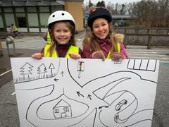 Saga og Nora fra 2.A har været med til at tegne Frydenhøjskolens nye cykelbane. Her står de med en af de første tegninger til tegninger.