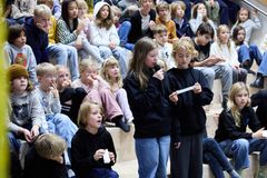 2 elever fra Skolerådet på 3. og 4. årgang står med en mikrofon og stiller udenrigsministeren spørgsmål om hans oplevelser fra PlanBørnefondens projektområde i Jakarta, Indonesien.