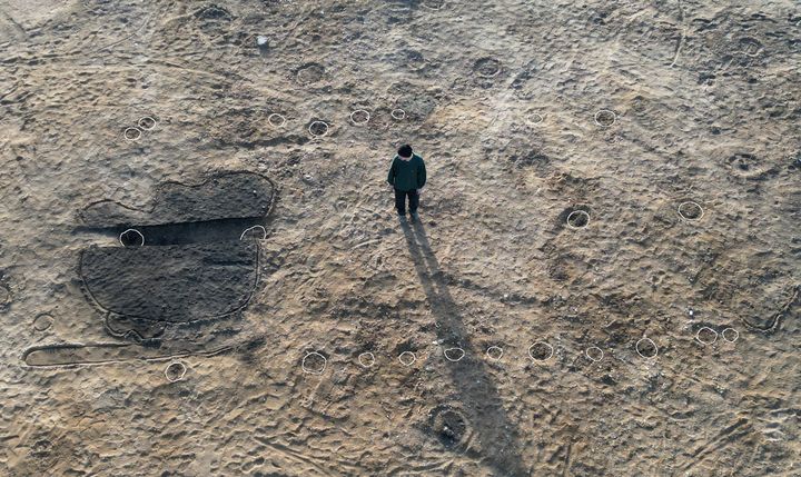 Dronefoto af et såkaldt midtsulehus, som indgår på top-10 over arkæologiske fund i 2024. Huset er kendetegnet ved, at taget er båret af én række stolper midt i huset. Den mørke plamage til venstre i billedet er en sænkning, som indeholdt ca. 17.000 korn af hvedearten emmer.