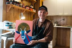 Esben Pretzmann i sit atelier med maleriet, som han har malet til Folkekirkens Nødhjælp: En superhelteged med laser-øjne.