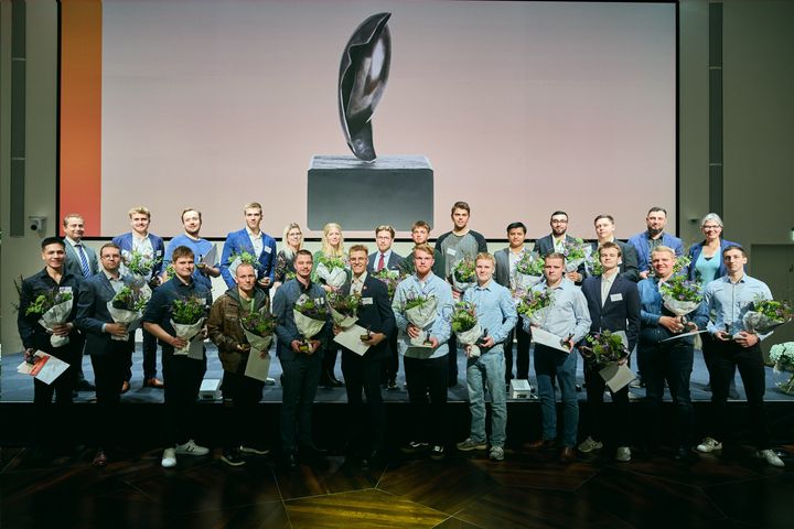 ML-prismodtagerne på scenen med blomster og diplomer foran et billede af en ML-prisstatuetten