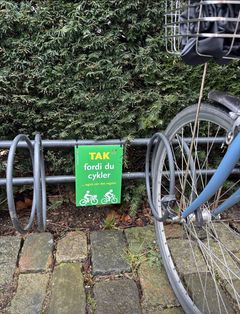 Plakaterne er placeret, hvor borgere og medarbejdere befinder sig, når de bevæger sig rundt. Her er budskabet Tak, fordi du cykler. Plakaten er placeret ved cykelstativ.