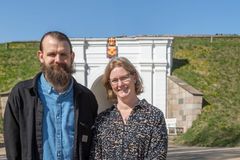 To personer foran en historisk port på en solrig dag.