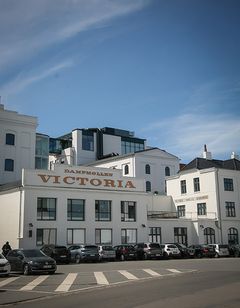 Dampmølle Victoria-bygning i Odense med hvid facade og flere etager.