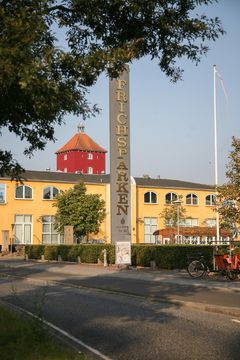 Gult industribyggeri i Frichsparken, Aarhus, med skilt og rød kuppel i baggrunden.