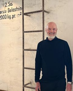 En mand står ved siden af en stige og smiler til kameraet.