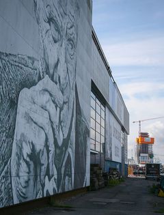 Vægmaleri af en tænksom person på en bygning ved Aarhus Havn.