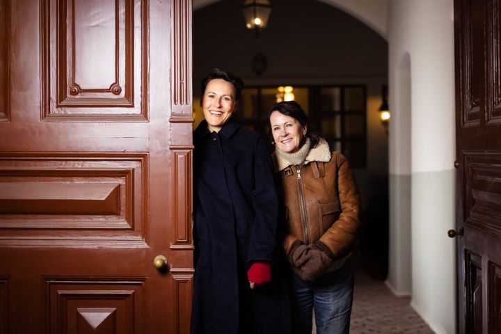 To personer står sammen og smiler ved en dør.