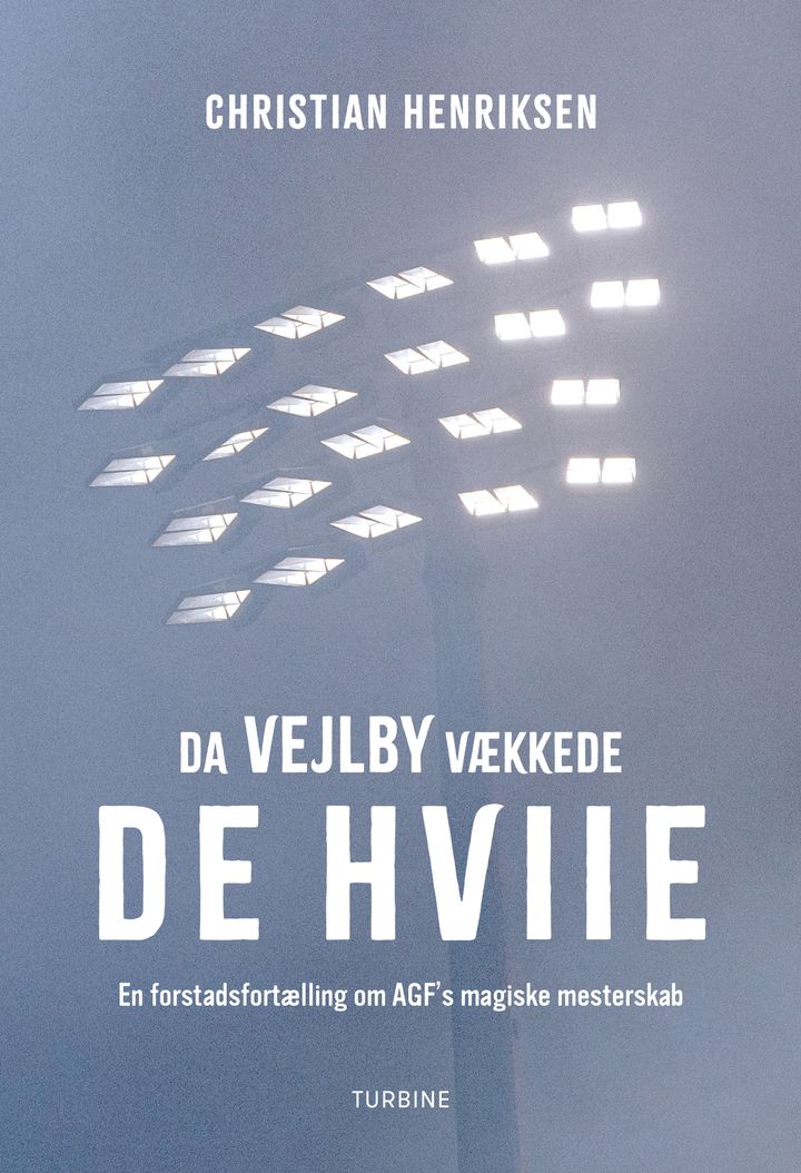 Forside af bogen "Da Vejlby vækkede de hviiie" med stadionprojektører i tåge.