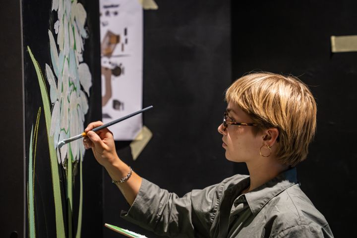 studerende maler en blomst på væggen i udstillingen