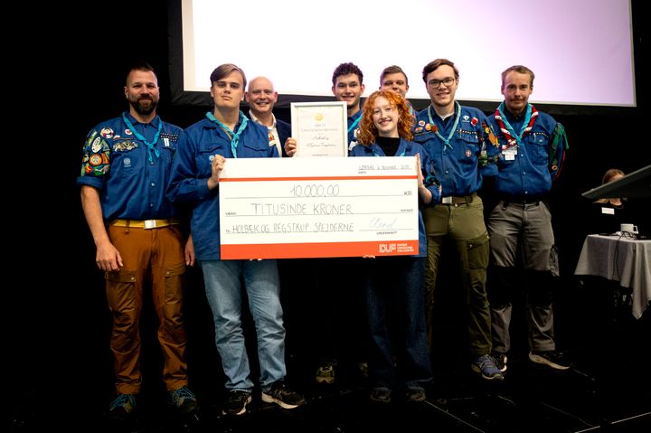 Holbæk- og Regstrupspejderne holder et diplom og en check til en værdi af 10.000 kroner, fordi de har vundet titlen som Årets Ungdomsforening 2025. På billedet ses repræsentanter fra gruppen sammen med kulturminister Jakob Engel-Schmidt, som overrakte prisen.