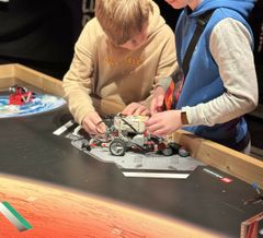 Elever er ved at sætte en anordning på deres robot til Mission 6: "Saml besætningen" ved Lego Space Challenge 2024