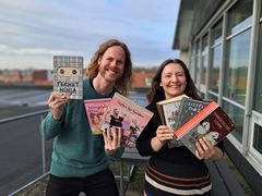 To personer viser en række bøger udenfor.