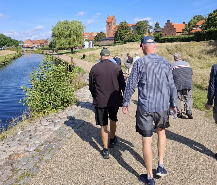 En gruppe mennesker går langs Susåen på en solrig dag.