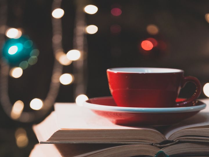 Billede af en kaffekop på en stak bøger med julelys i baggrunden