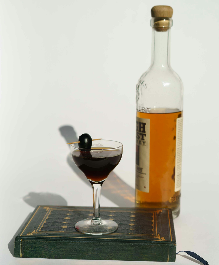 Billede af en flaske, et cocktailglas og en bog