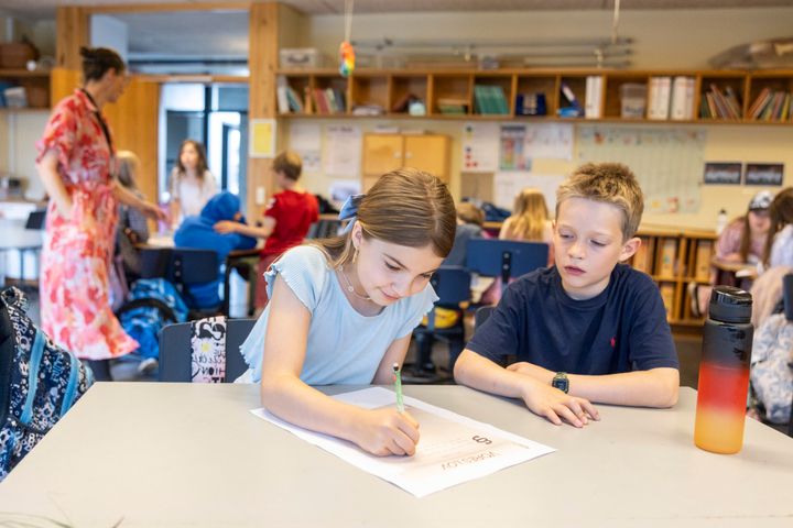 To børn arbejder sammen ved et bord i et klasseværelse