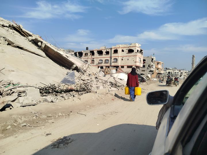 Kvinde fragter vand i ruinerne i Beit Lahia i Gaza.