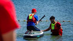 Frivillige lærer børn at stå på SUP-board i Børkop på Red Barnets Ferielejr.