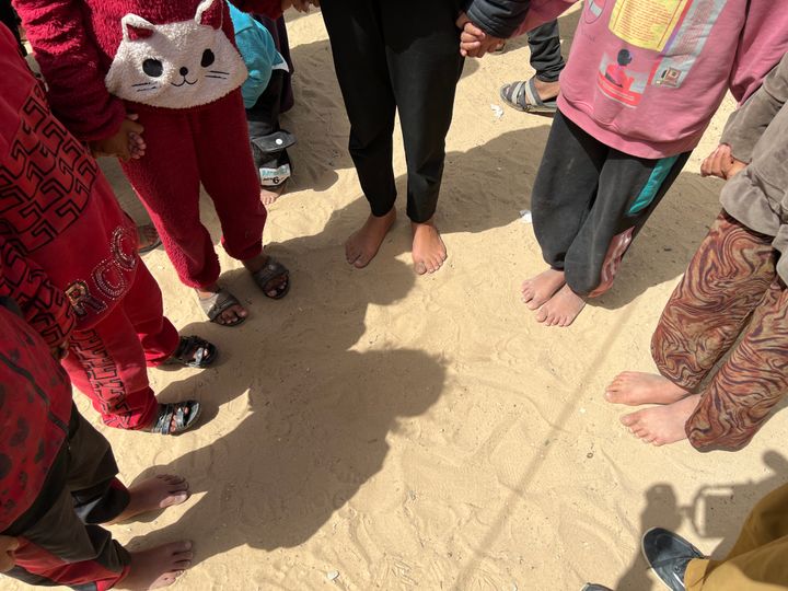 Børn i en rundkreds på en strand i Rafah.