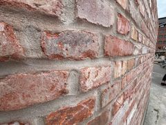Nærbillede af en mur bygget med forskellige genbrugssten.