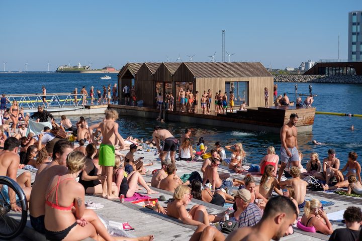 Mange mennesker soler sig og bader ved en Sandkaj Badezon.