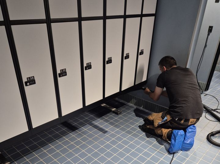 Person installerer bænk foran omklædningsskabe i Kampsportens Hus på Nørrebro.