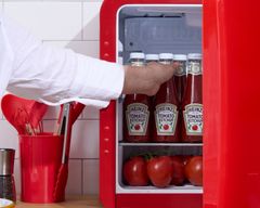 En person placerer Heinz tomatketchupflasker i et rødt køleskab.
