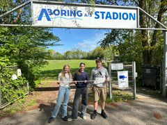 Elias, Maja og Nicoline besøgte Hejnsvig Stadion for at måle op til det store skilt, der skal markere, at Legens Festival kulminerer ved stadionet. Foto: Billund Kommune